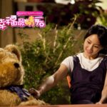 Woman smiling while petting large teddy bear