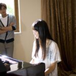 Woman playing piano while man watches