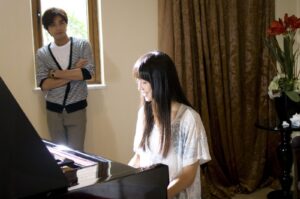 Woman playing piano while man watches