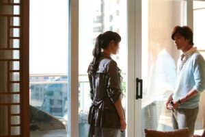 Man and woman talking by apartment balcony door