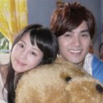 Smiling couple hugging large teddy bear