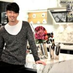 Smiling man leaning on marble kitchen counter