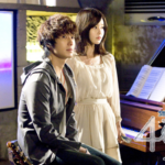 Two people beside piano with sheet music
