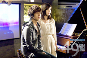 Two people beside piano with sheet music