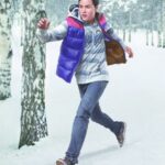 Young man running through snowy birch woods