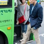 Young man and woman boarding green bus