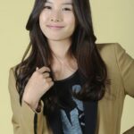 Smiling woman in blazer against yellow background