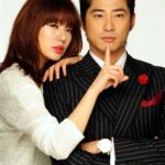 Woman leaning on suited man, finger to lips