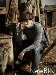 Man in sweater seated among wooden decor.