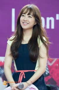 Smiling person with long hair and microphone.