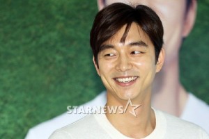 Smiling man in casual sweater, green background.