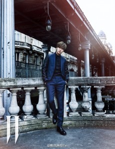 Man in stylish suit posing by railing.