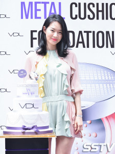 Woman standing beside a decorated cake.