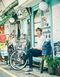 Young man sitting near a bicycle in street.