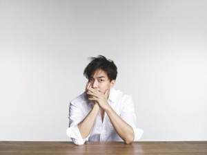 Young man sitting thoughtfully at a table.