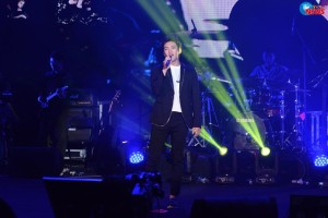 Singer performing on stage with band.