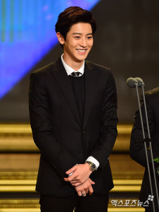 Young man in black suit smiling at podium