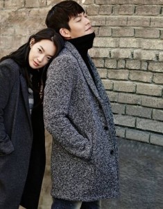 Couple leaning against a brick wall together.
