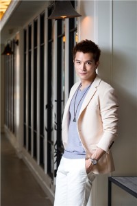 Man in suit posing in well-lit hallway.