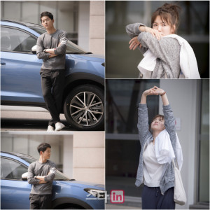 Two people posing by a blue car.