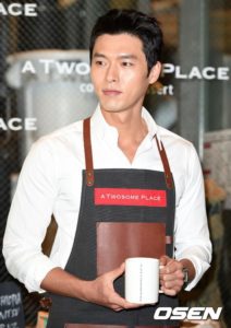 Man in apron holding a coffee mug.