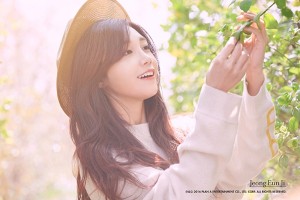 Woman smiling and reaching for green leaves.