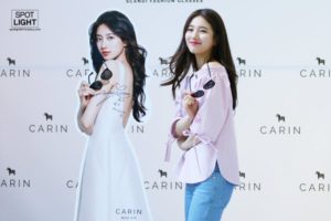 Woman poses with sunglasses near a display.