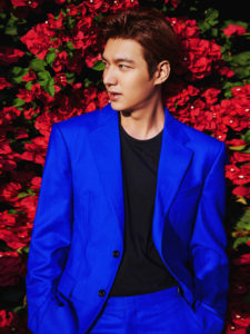 Man in blue suit against red flowers.