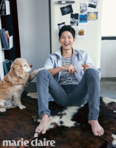 Smiling person sitting with dog on rug.
