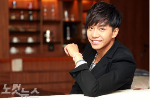 Smiling man in a black suit, indoors.