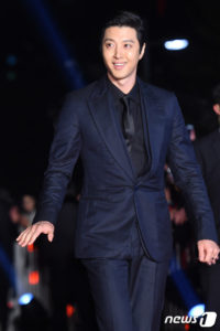 Man in a suit smiling at event.