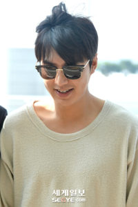 Smiling person wearing sunglasses and loose sweater.