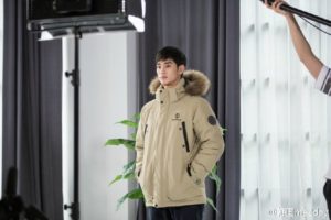 Man in a beige winter jacket posing indoors.