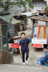 Young man walking in a cluttered alley.