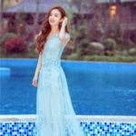 Woman in a flowing blue dress by water.