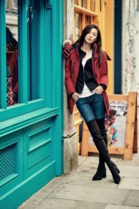 Woman in red jacket against colorful storefront.