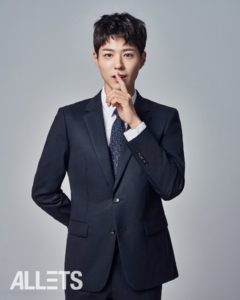 Man in suit with finger to lips.