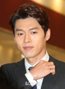 Man adjusting his suit jacket, serious expression.