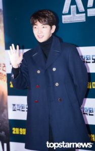 Person in blue coat waving at an event.