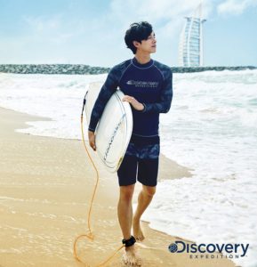 Surfer walking on beach with surfboard.