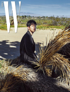 Model sitting on a tree trunk outdoors.