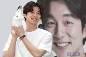 Smiling man holding a rabbit plush toy.