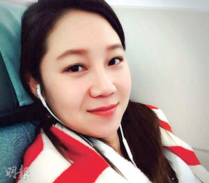 Woman with headphones, smiling in a cozy setting.