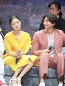 Two people sitting on stage, smiling together.