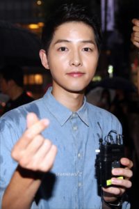 Young man making heart gesture, holding microphone.