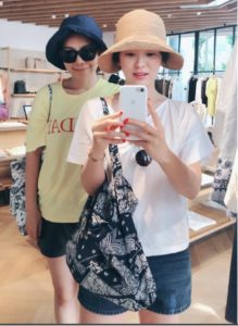 Two friends taking a selfie in clothing store.