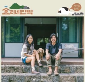 Two people and a dog smile outdoors.