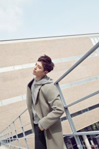 Man in stylish coat poses outdoors.