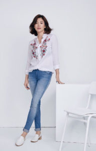 Woman in embroidered shirt and jeans.