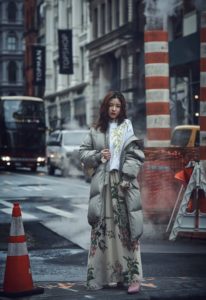 Woman in floral dress and gray puffer jacket.
